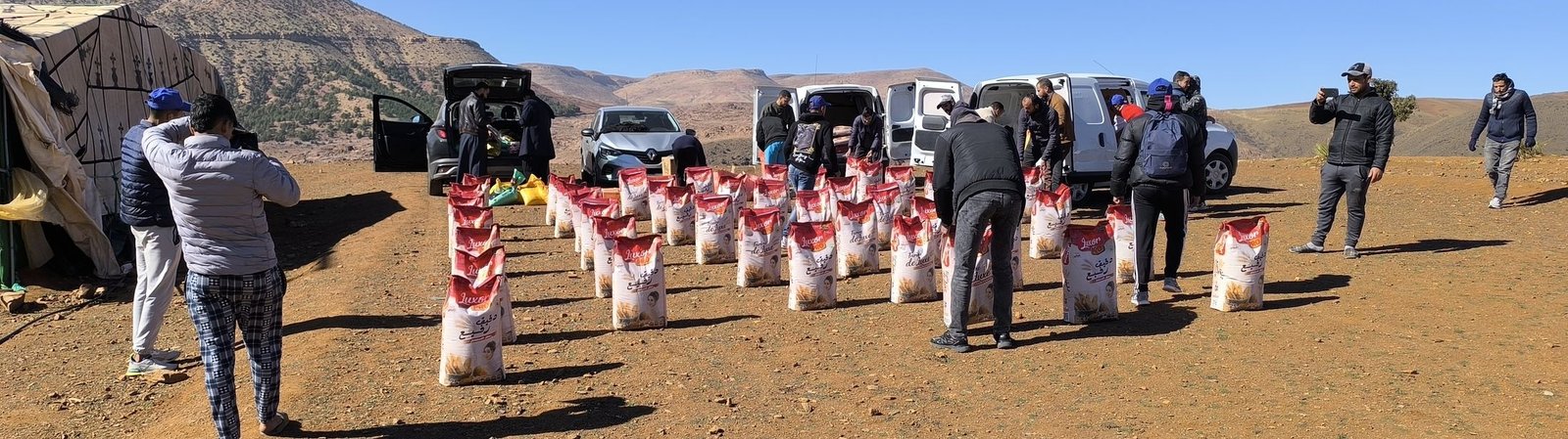 Hundreds of aid sacks laid out in rows on the ground with mountains behind