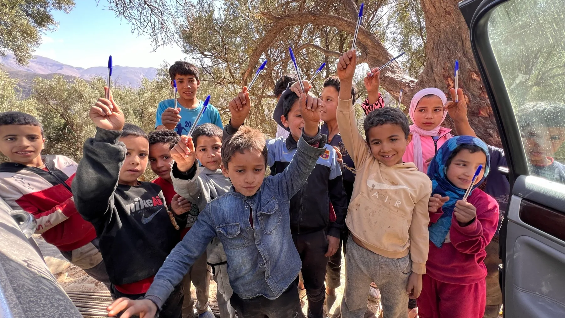Children in the High Atlas Mountains raise the pens they received during a School Aid field mission
