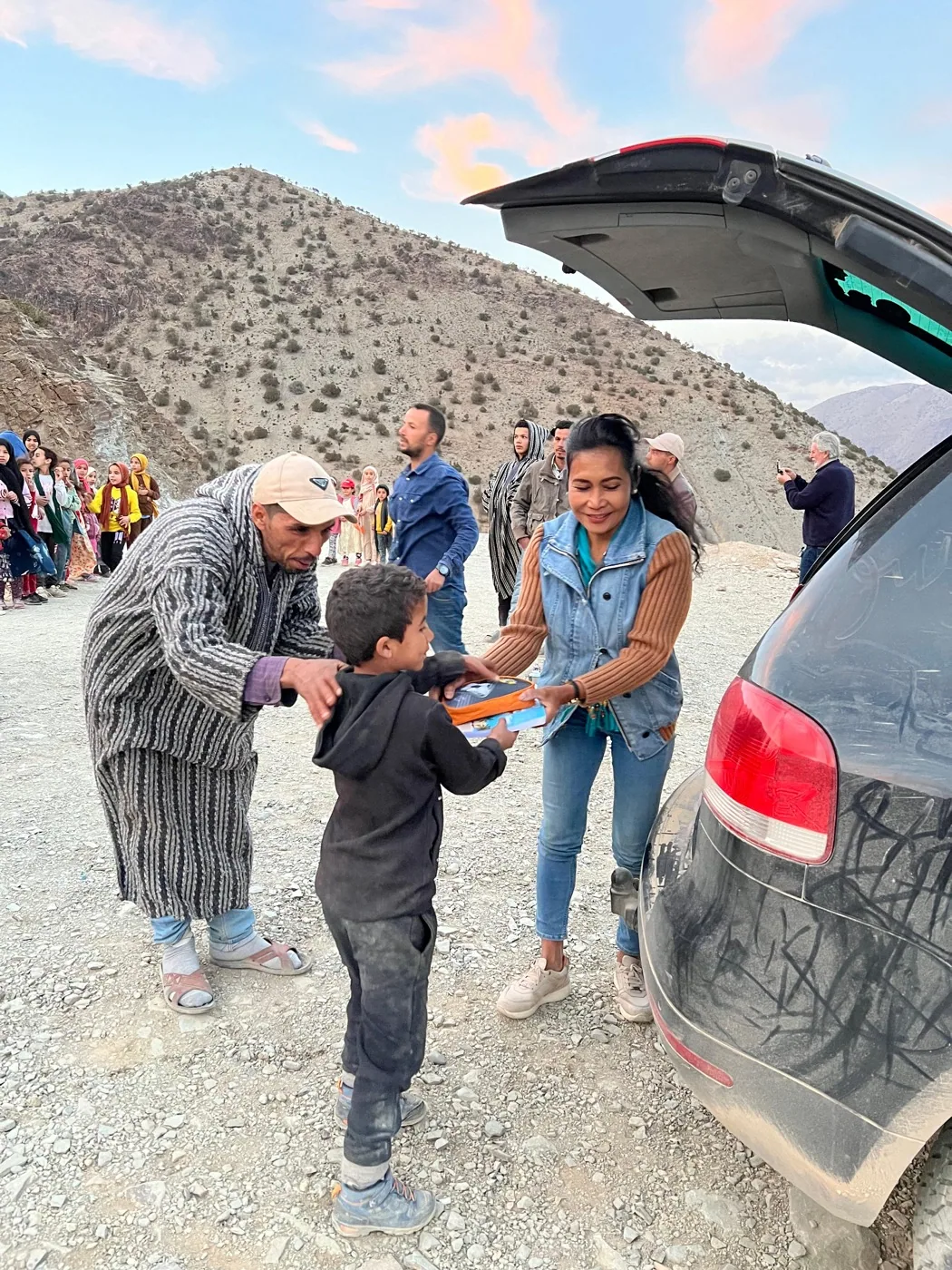 A School Aid learning kit is handed directly to a child during a community distribution in the High Atlas Mountains