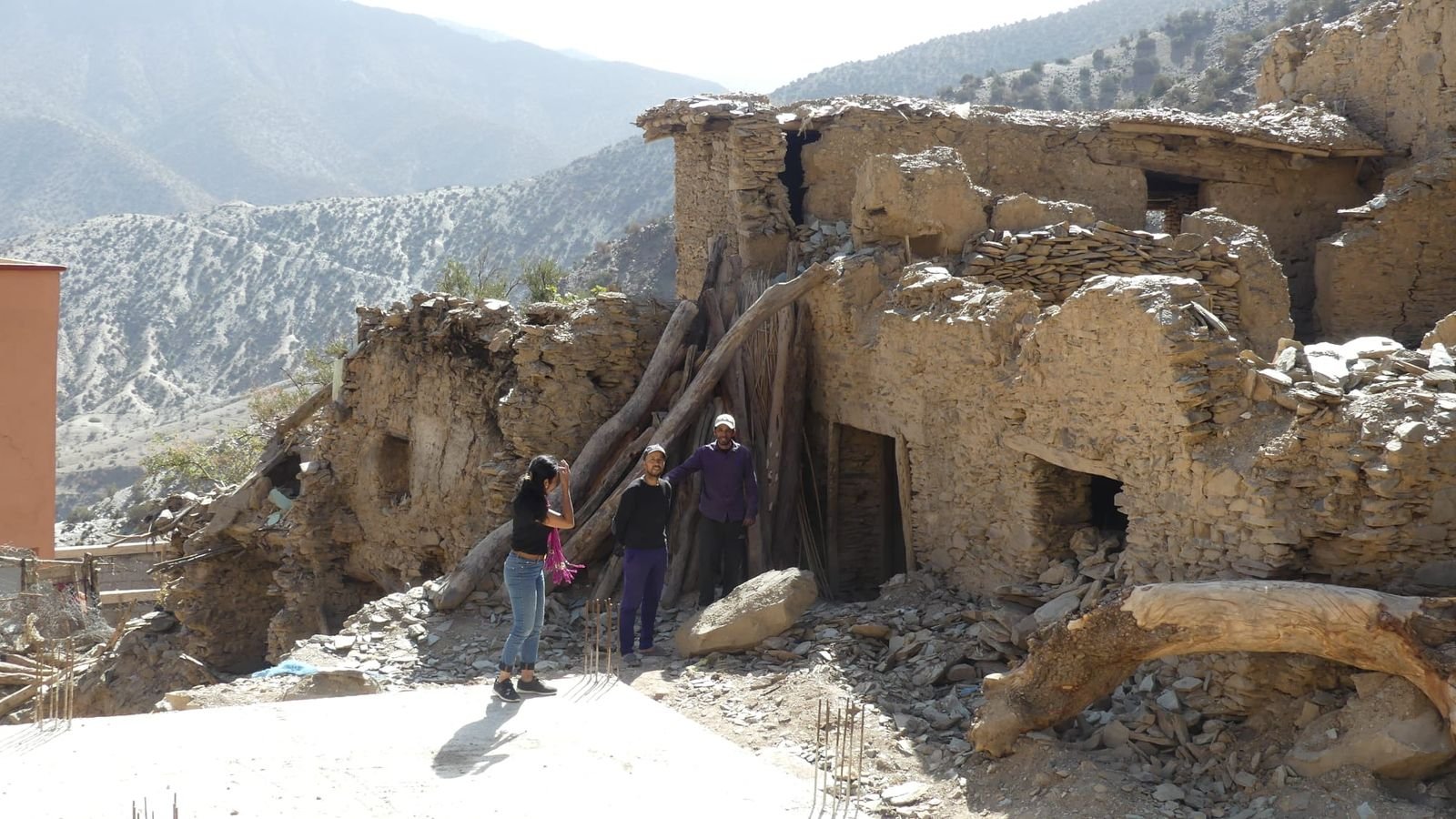 Earthquake-damaged stone houses on a snow-dusted High Atlas hillside