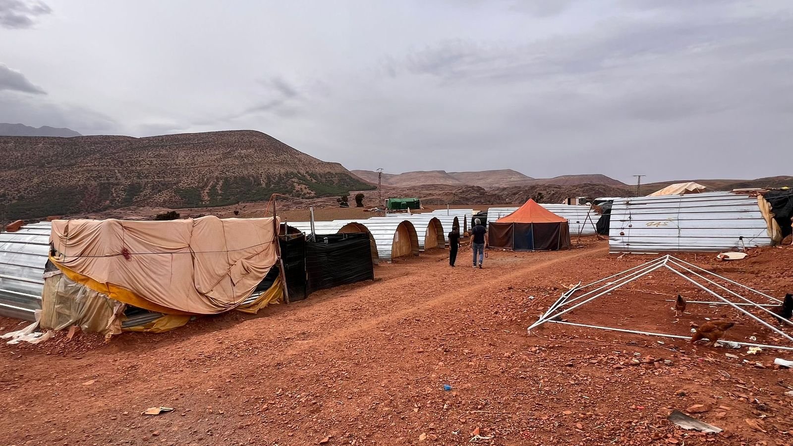 A row of emergency tent and tin shelters in an arid mountain camp