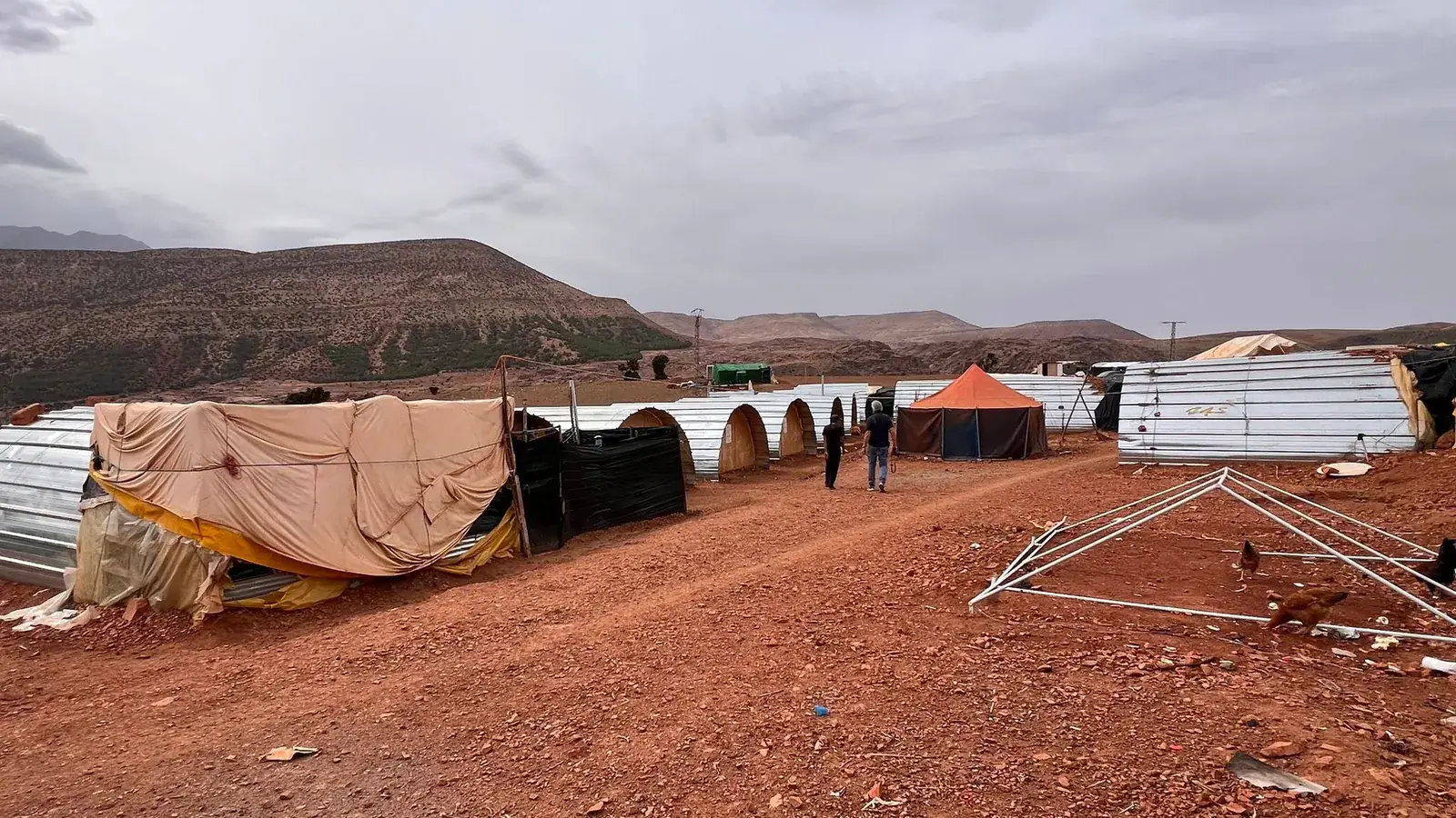 A row of emergency tent and tin shelters in an arid mountain camp