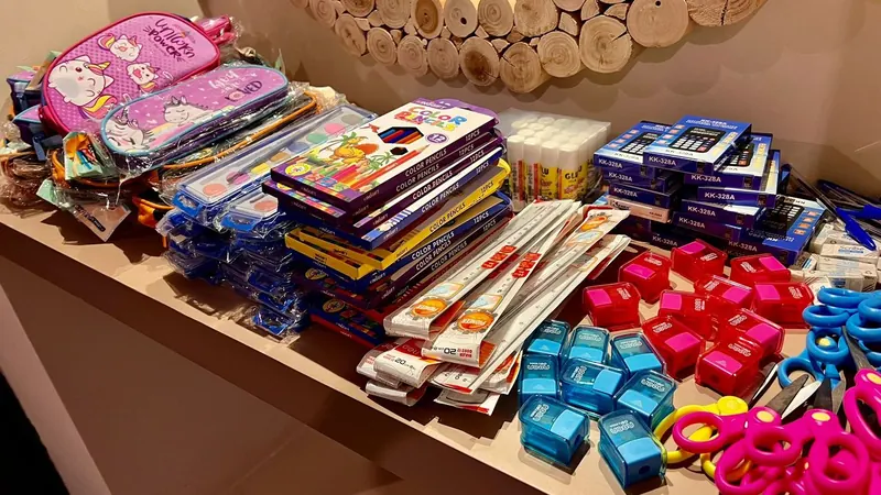 A table covered with notebooks, pencil cases and colouring sets being sorted into school kits