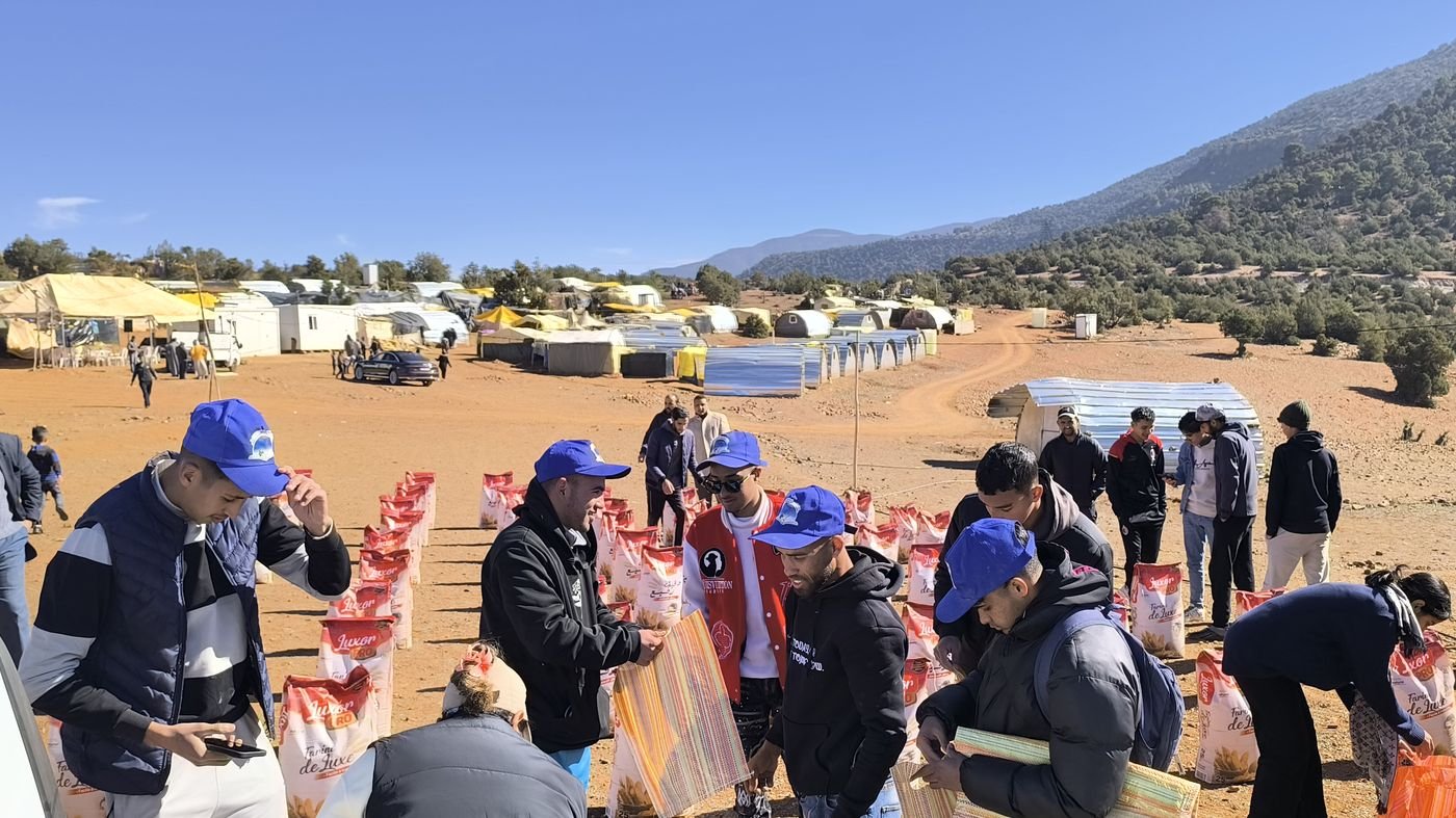 Volunteers working the distribution line with the camp and mountains behind