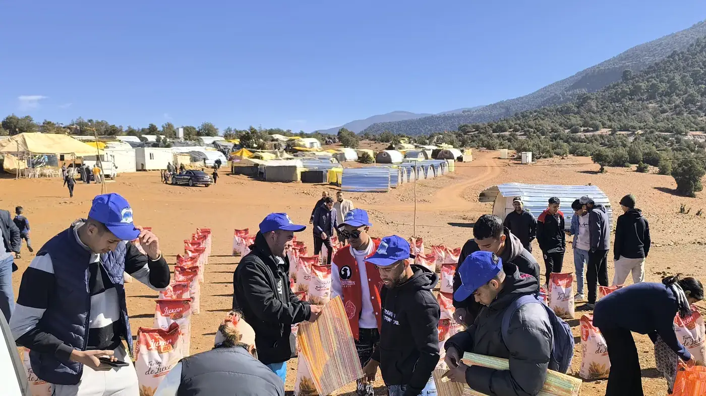 Volunteers working the distribution line with the camp and mountains behind